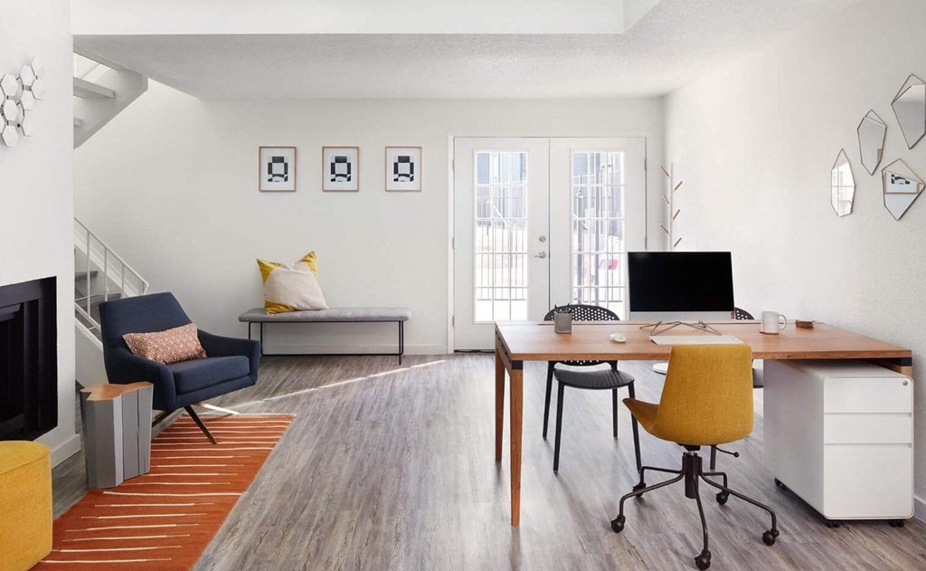 a home office with a desk and chair and a couch in the background
