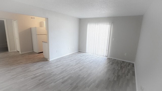 an empty living room with a refrigerator and