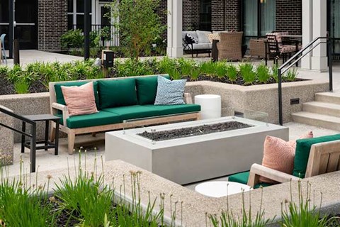A patio with a green couch and a fire pit.