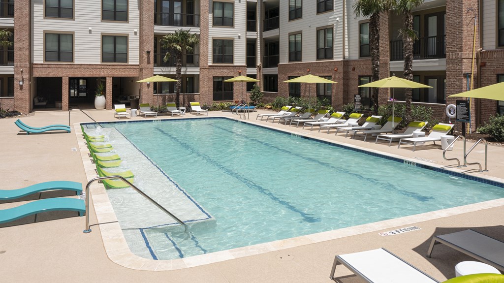 a swimming pool with lounge chairs and a building in the background