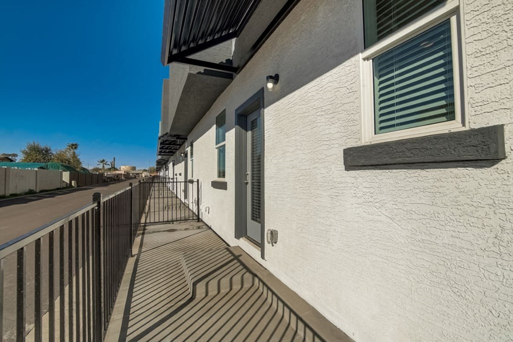 a balcony with a fence and a building next to a street