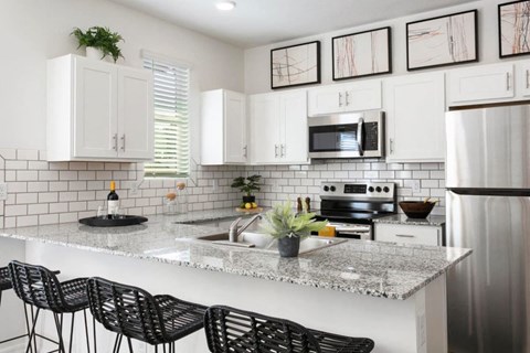 a kitchen with white cabinets and a marble counter top
