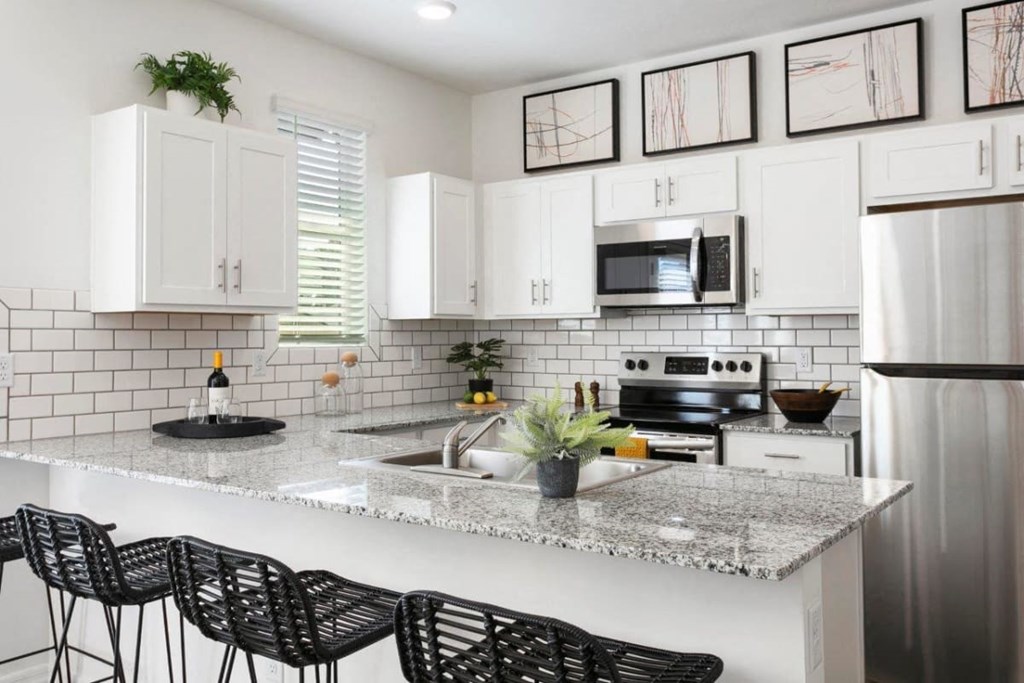 a kitchen with white cabinets and a marble counter top