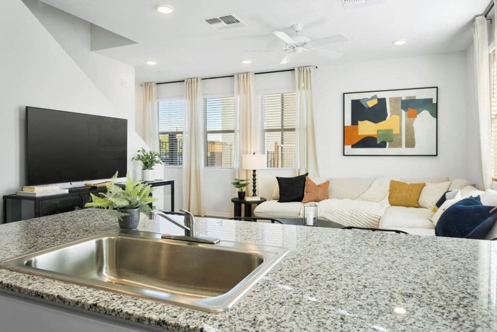 a kitchen counter with a sink in front of a living room