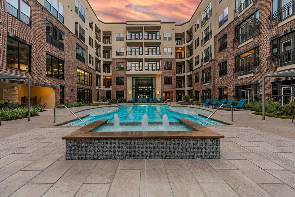 A courtyard with a pool and a fountain in the middle of it.