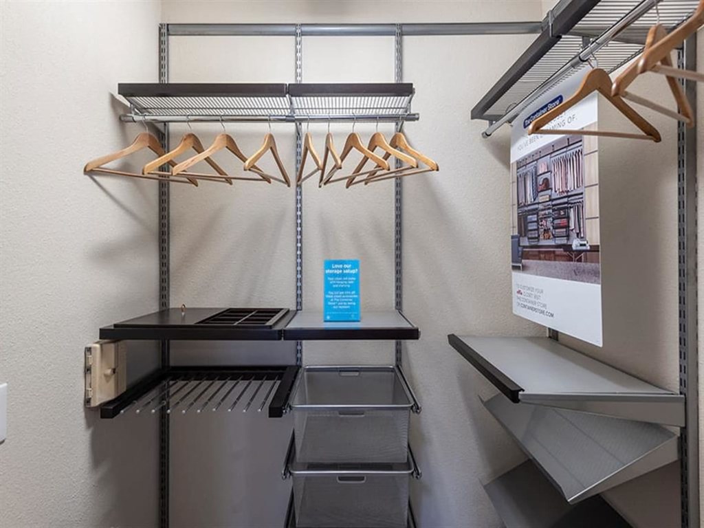 a walk in closet with a refrigerator and racks