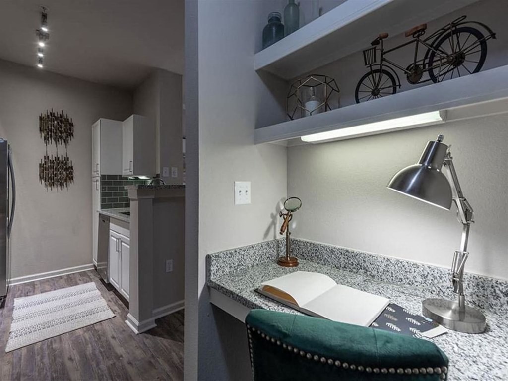 a kitchen and a desk with a lamp and a book