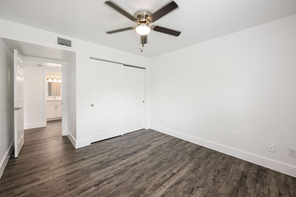 an empty living room with white walls and a ceiling fan