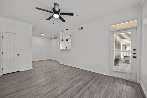 a living room with white walls and a ceiling fan