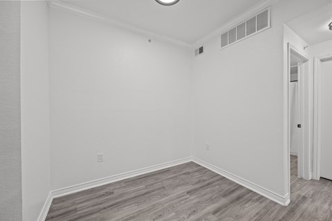 an empty room with white walls and wood flooring