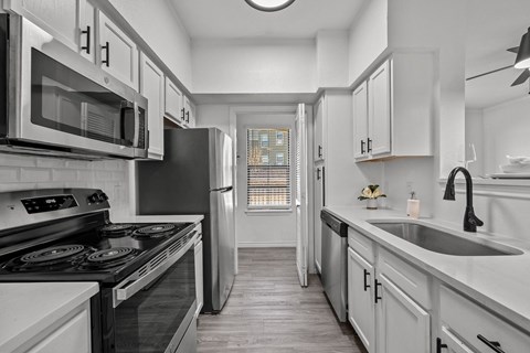 an empty kitchen with white cabinets and stainless steel appliances