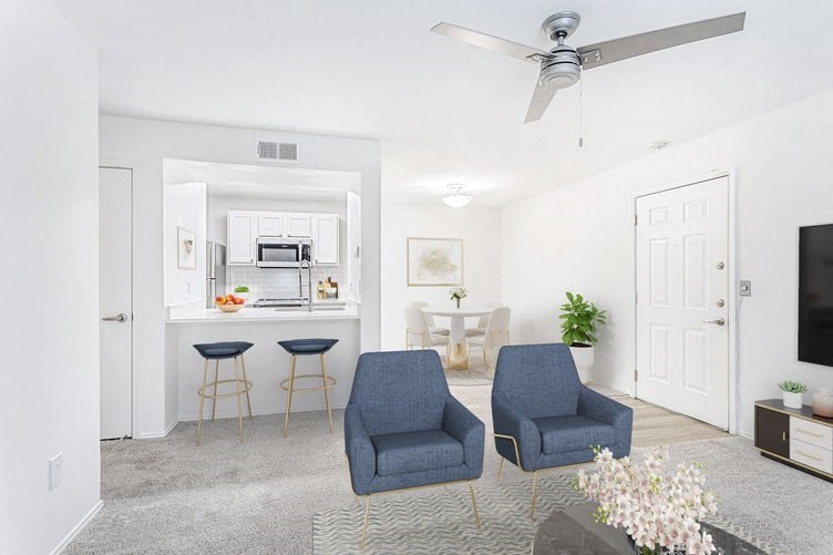 a living room with two blue chairs and a kitchen in the background