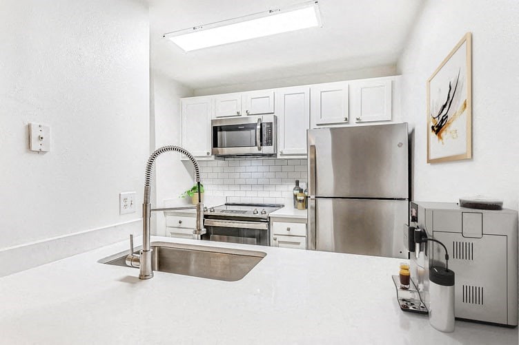 a kitchen with a white counter top and a stainless steel refrigerator