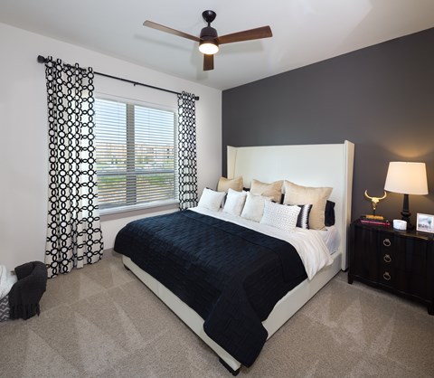 A bedroom with a large bed and a ceiling fan.