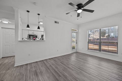 an empty living room with a ceiling fan and a window