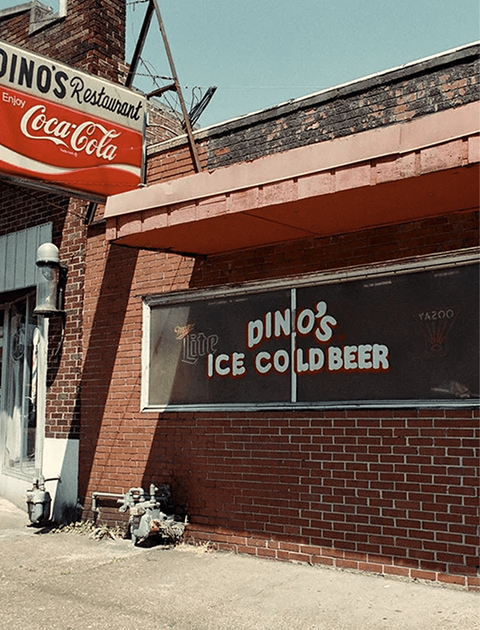 A diner with a Coca-Cola sign on the left and a Pinos Restaurant sign on the right.