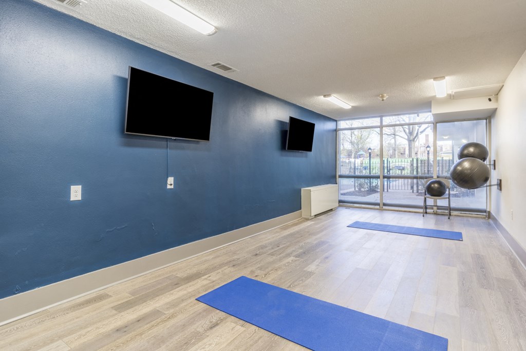 a spacious yoga studio with a wall mounted tv and yoga mats on the floor