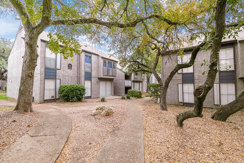 a courtyard with trees and a building in the background