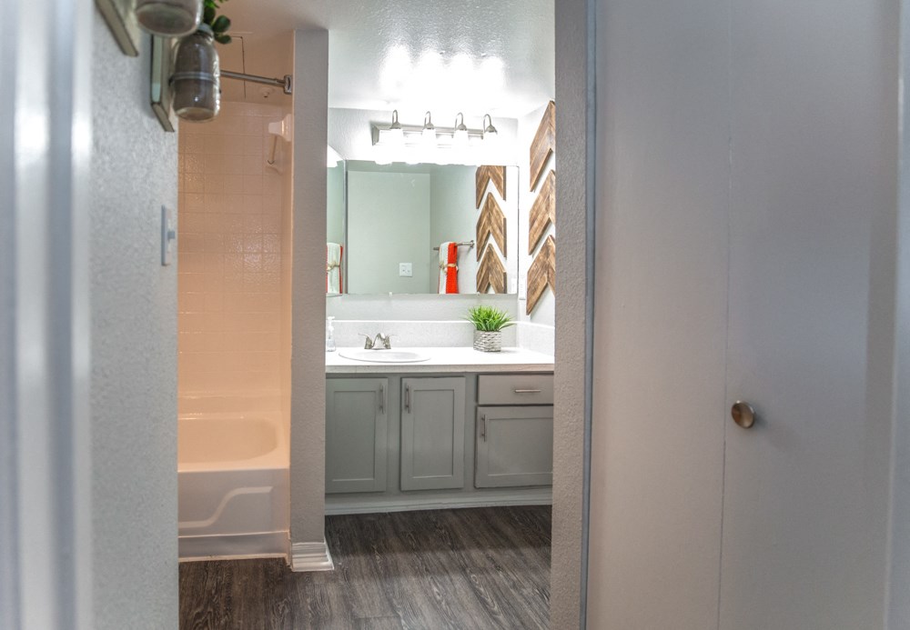 a bathroom with gray cabinets and a white bathtub