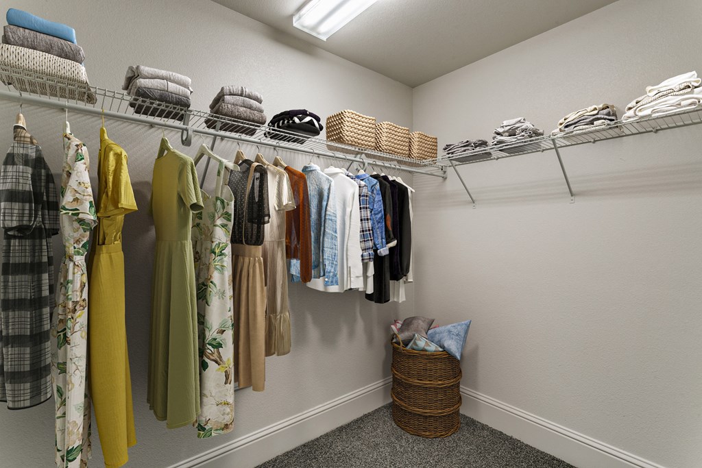a closet with clothes hanging on a rack and a basket on the floor