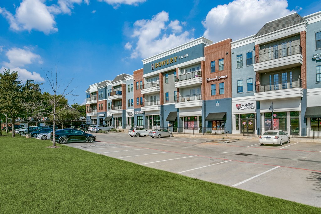 an empty parking lot in front of a building with cars parked in front