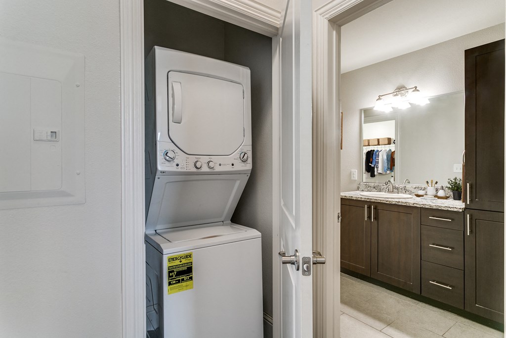 a white washer and dryer sitting on top of a refrigerator in a bathroom