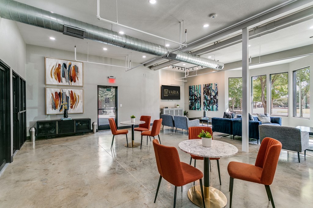 a lobby with tables and chairs and a living room with large windows