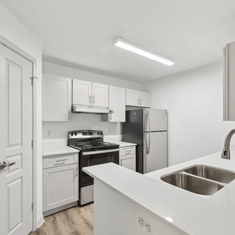 A modern kitchen with white cabinets and stainless steel appliances.