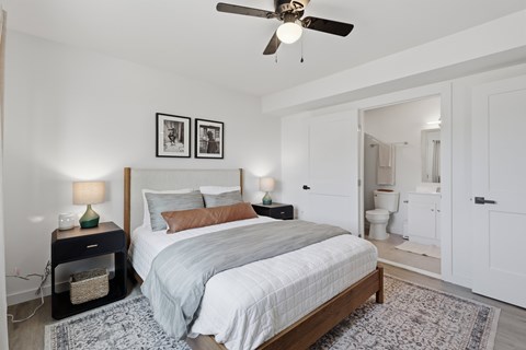 A bedroom with a bed, nightstands, and a ceiling fan.