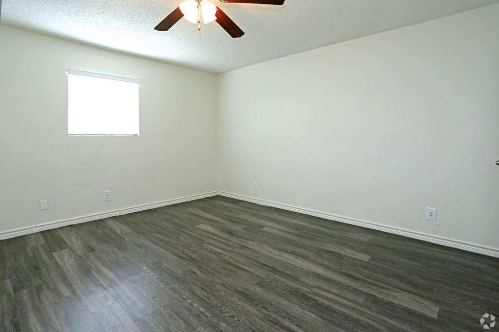 an empty room with a ceiling fan and a window