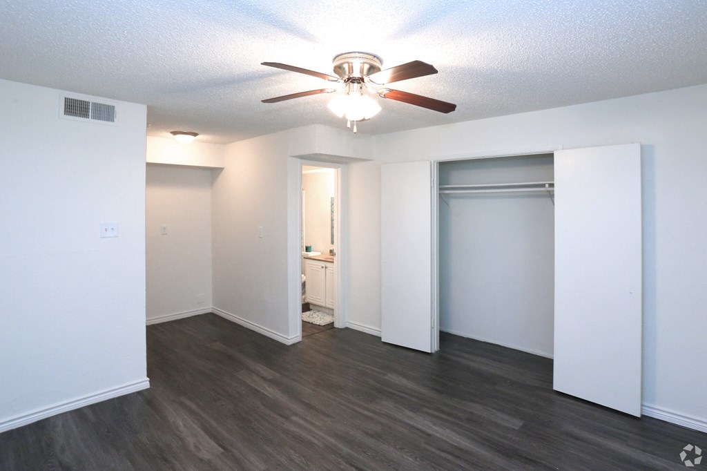 an empty living room with a ceiling fan