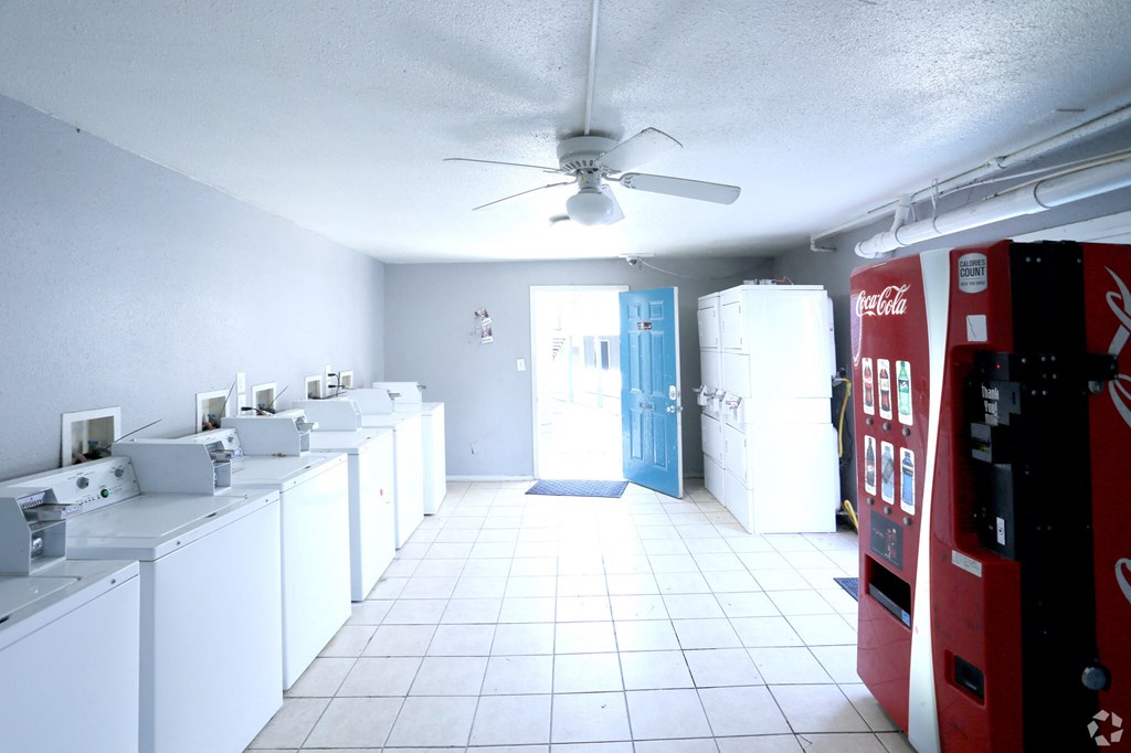 an empty laundry room with white appliances and a red coke machine
