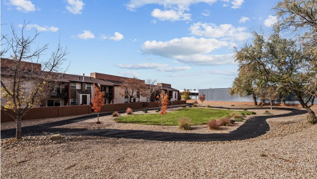 a circle of grass and trees in front of a building