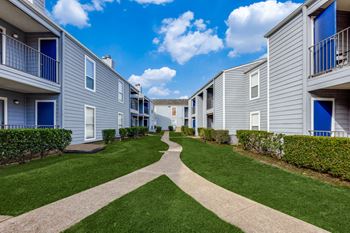 A row of grey apartment buildings with blue doors and windows.