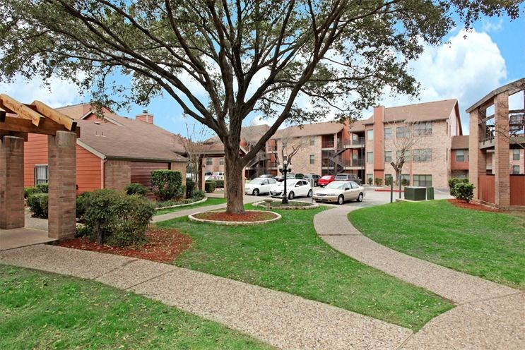 an apartment building with a tree and a sidewalk
