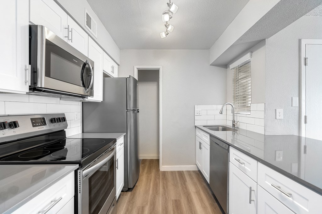 an empty kitchen with stainless steel appliances and white cabinets