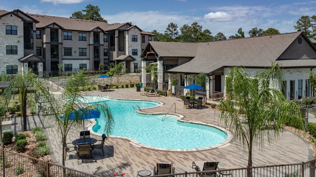 A large outdoor swimming pool surrounded by lounge chairs and trees.