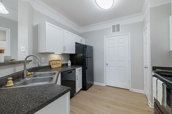 A kitchen with black appliances and white cabinets.
