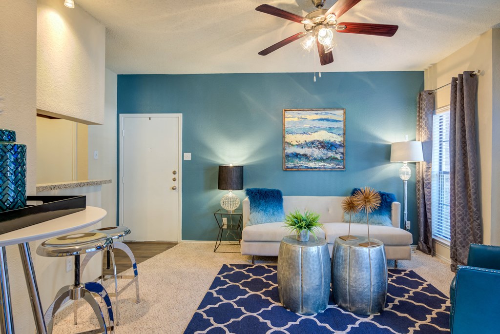 a living room with blue walls and a ceiling fan
