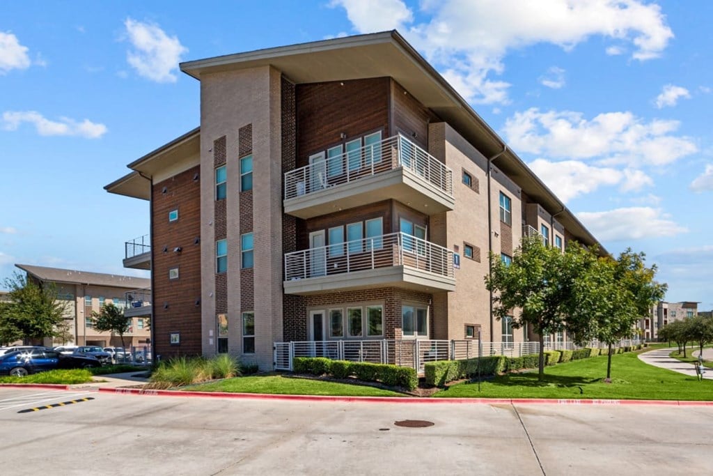 A large apartment building with a parking lot in front.
