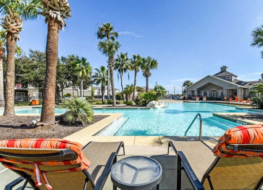 a large swimming pool with chairs and palm trees