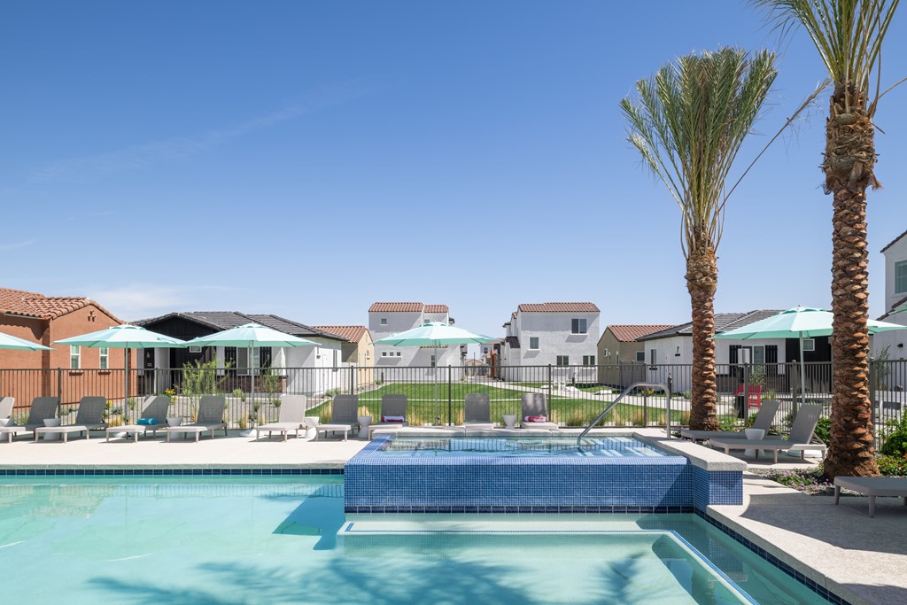 A swimming pool surrounded by palm trees and lounge chairs.
