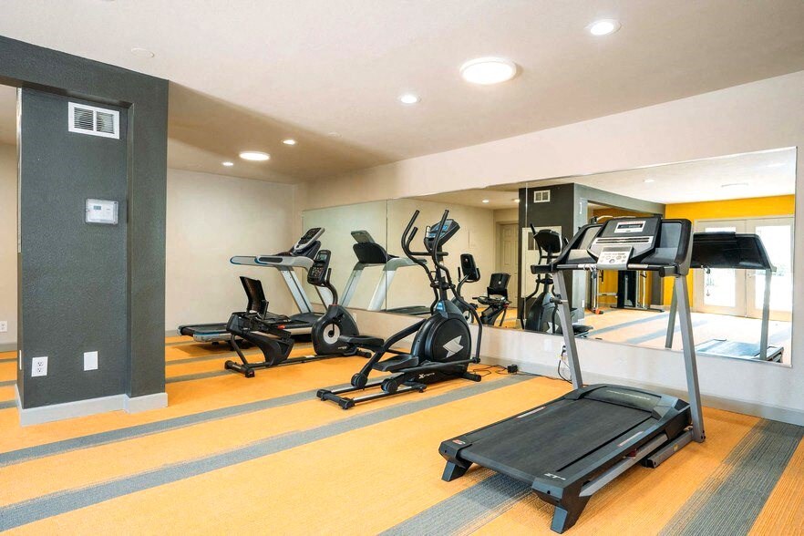 a gym with cardio equipment on the floor and a mirrored wall