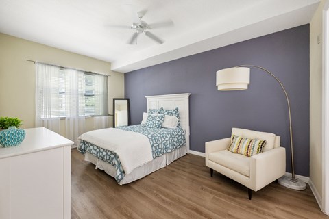 a bedroom with a bed and a chair and a ceiling fan