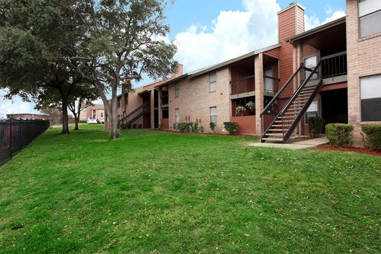 an apartment building with a green yard and stairs