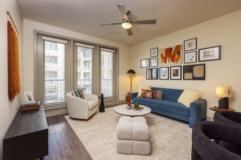 A living room with a blue couch, a piano, and a ceiling fan.