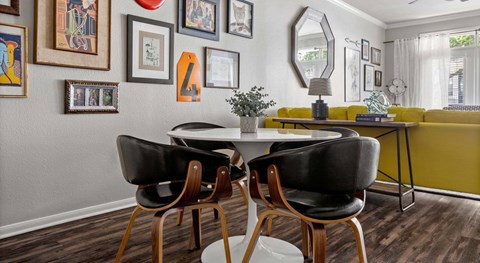 A dining room with a yellow sofa and a table with four chairs.