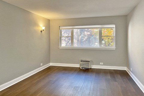 an empty living room with a window and wooden floors