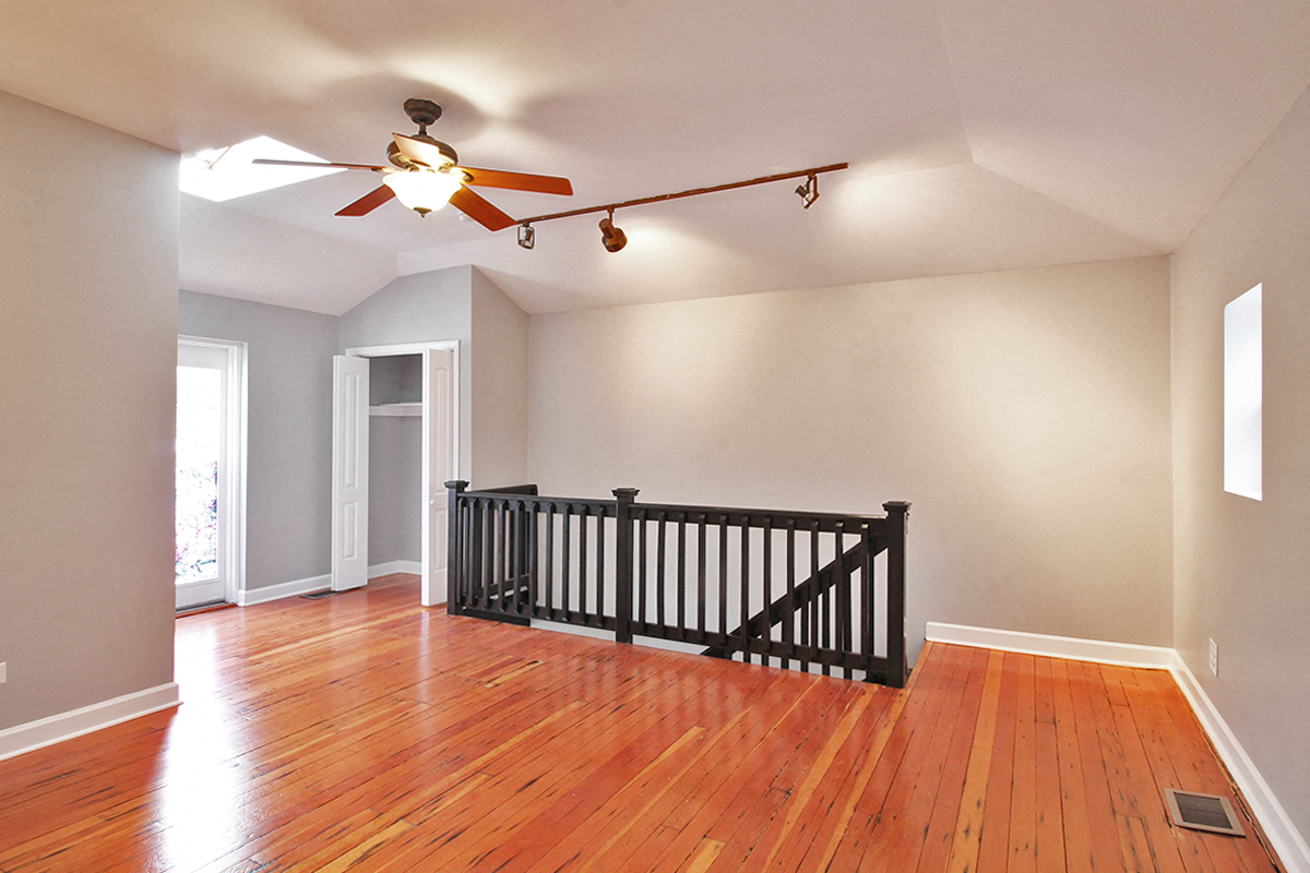 A room with a ceiling fan and wooden floors.