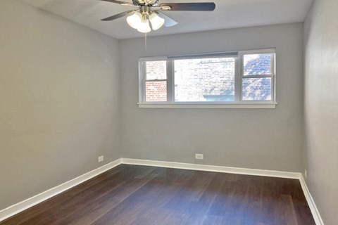 an empty room with a window and a ceiling fan